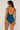 Woman wearing a teal swimsuit against a plain background