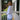 Woman in a white sweater standing on a porch with a house and garden in the background