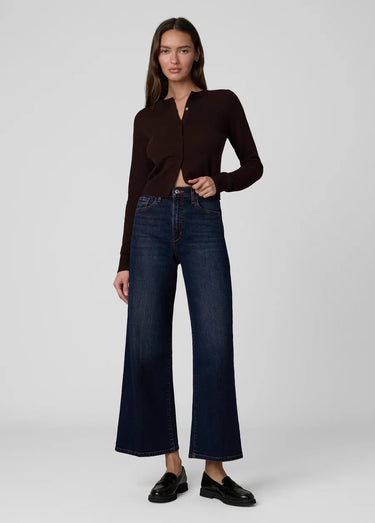 a woman wearing a dark brown cardigan and dark blue jeans on a white background