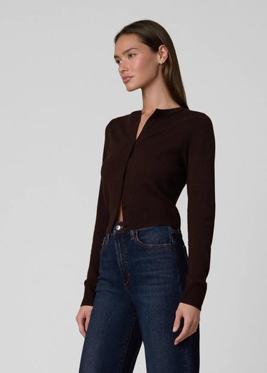 a woman wearing a dark brown cardigan and dark blue jeans on a white background