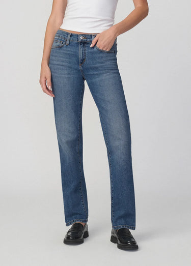 Person wearing blue jeans and black shoes on a white background