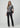 Black slim bootcut jeans styled with a metallic silver top and pointed-toe black heels on a model.