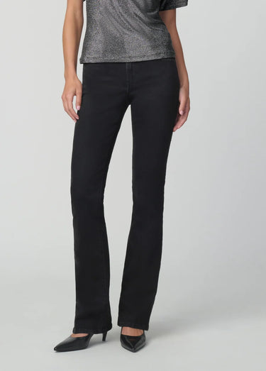 Black slim bootcut jeans styled with a metallic silver top and pointed-toe black heels on a model.