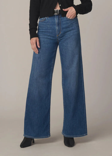Person wearing blue wide-leg jeans on a neutral background