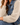 a woman wearing a denim jacket with grey knit sleeves and white jeans on a white background