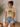 Woman wearing a yellow t-shirt with a peach graphic and 'Peachy' text, standing indoors.
