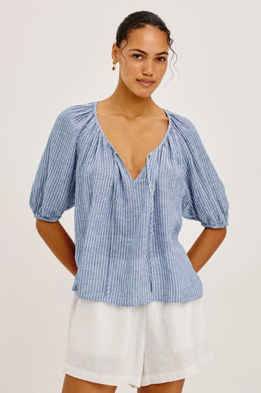 Woman wearing a barletta stripe blouse with puffed sleeves on a white background