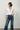 Woman wearing a white blouse and blue jeans against a plain background