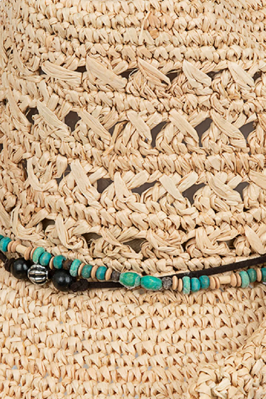 Close-up of a woven straw hat with decorative beads.