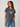 A woman wearing a dark gray heathered t-shirt with a white and black leopard-print heart graphic on the chest, paired with blue jeans, against a light gray studio background