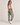 A woman modeling olive green jogger sweatpants with white embroidered stars on the legs and a brown embroidered star on the back pocket, paired with a white tank top and white sneakers against a neutral studio background.