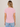 A woman viewed from behind wearing a light pink short-sleeve crewneck t-shirt and light blue jeans, standing against a neutral beige studio background.