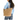A woman wearing a light blue sweater and jeans carries a large tan embossed leather tote bag with beige handles and trim against a plain white background.