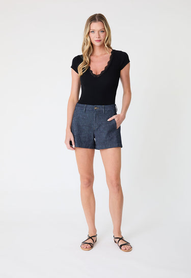 Woman wearing a black top and denim shorts on a white background