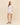 Woman wearing a white shirt and shorts set on a beige background