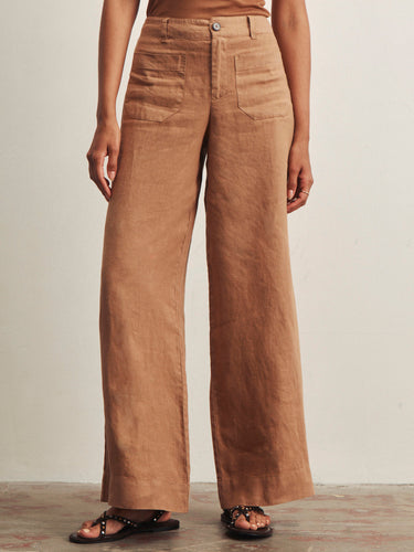 a woman wearing light brown wide leg pants and studded black sandals