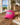 Pink cap with colorful logo on a wooden surface near a beach view