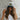 Woman wearing a cap with 'Let the Good Times Roll' text against a stone wall.