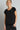 Woman wearing a black top and pants against a gray background
