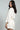 Woman wearing a white outfit with a belt on a gray background