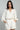 Woman wearing a white outfit with a belt on a gray background
