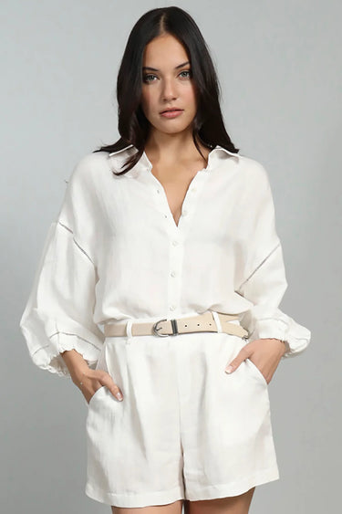 Woman wearing a white outfit with a belt on a gray background