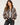 a woman wearing a reversible baseball leopard jacket with black jeans on a neutral background.