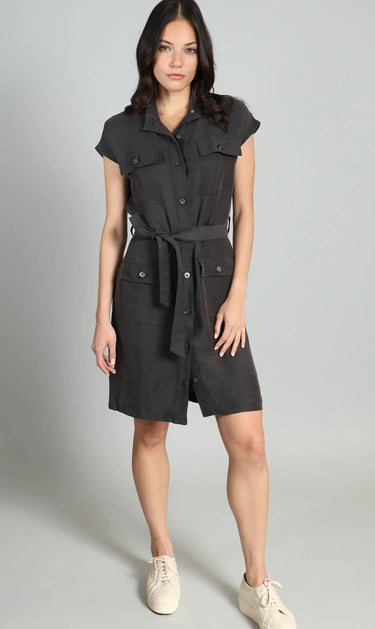 Woman wearing a black sleeveless dress with buttons on a gray background