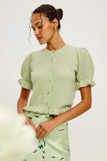 a woman wearing a green short sleeve sweater with ruffle trimmed puff sleeves