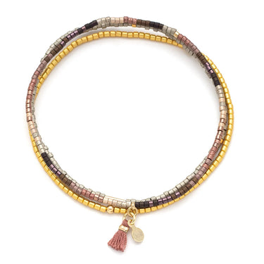 Multicolored beaded bracelet with a tassel charm on a white background