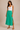 A woman wearing a jade midi skirt and white tank on a neutral background