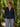 Woman wearing a navy blue hoodie and light blue jeans standing in a garden.