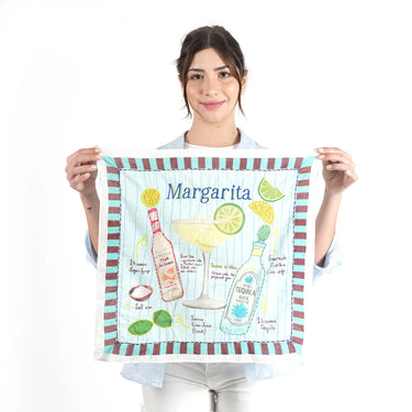 Woman holding a 'Margarita' themed tea towel with illustrations of a cocktail and ingredients.