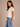 a woman wearing a crewneck cropped boxy fit tee in pale pink with jeans on a neutral background