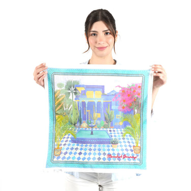 Woman holding a colorful scarf with a design of a garden scene on a white background