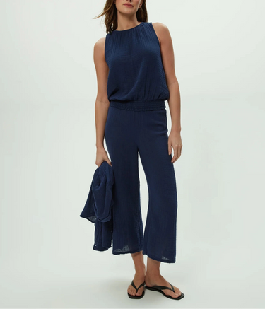 Woman wearing a navy blue sleeveless top and cropped wide-leg pants on a white background