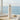 White water bottle with silver cap on a windowsill with a view of the ocean.