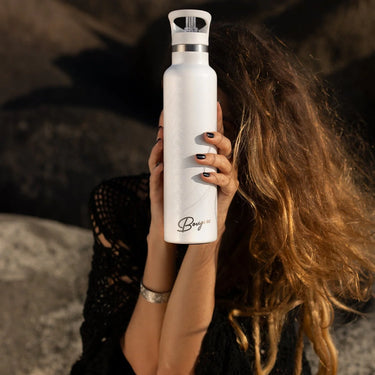A woman holding a “bougie” branded scale printed waterbottle on the beach