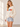 A woman wearing a white sweater with “HO!HO!HO!” written along the arms and shoulders in colorful letters.