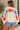 A woman wearing a white sweater with “Merry Christmas” written along the arms and shoulders in colorful letters.