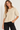 a woman wearing a knit short sleeve seater with gold sequins and black pants on a white background.
