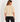 a woman wearing a knit short sleeve seater with gold sequins and black pants on a white background.
