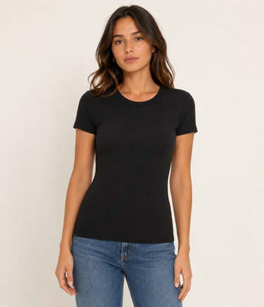 A woman modeling a fitted black short-sleeve crewneck t-shirt with blue jeans, standing against a plain off-white studio background.