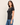 A woman modeling a fitted short-sleeve crew-neck t-shirt in a washed black or charcoal color, paired with blue jeans, against a plain off-white studio background.