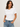 Woman wearing a white t-shirt and blue jeans against a plain background