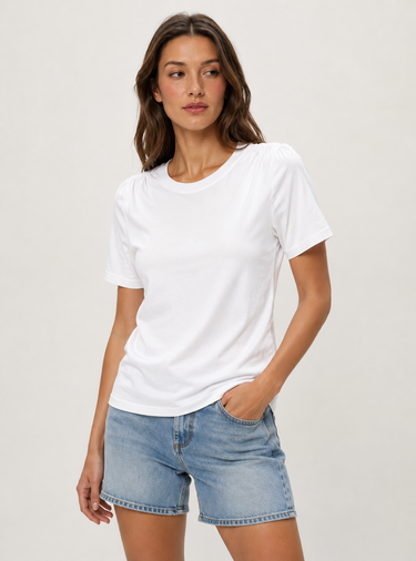 Woman wearing a white t-shirt and denim shorts on a plain background
