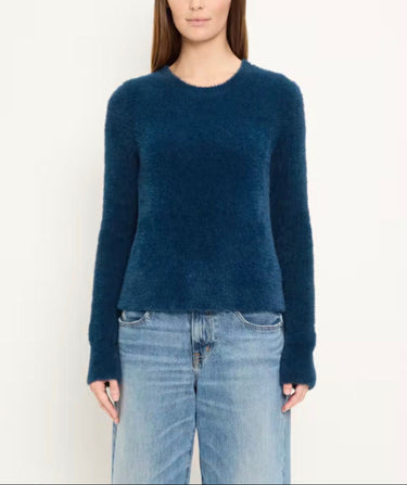 a woman wearing a brushed yarn crewneck sweater in a deep blue and blue jeans on a white background.