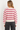 A woman wearing a cashmere beige pink-striped sweater on a white background.