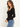 A side angle of a woman wearing a black square neck long sleeve top and blue jeans on a white background