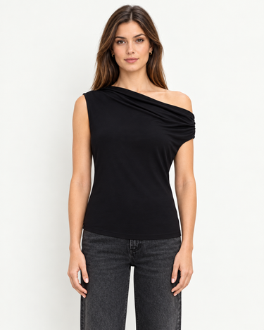 Delilah black drape top, front view showing asymmetrical off-the-shoulder neckline with dark jeans
